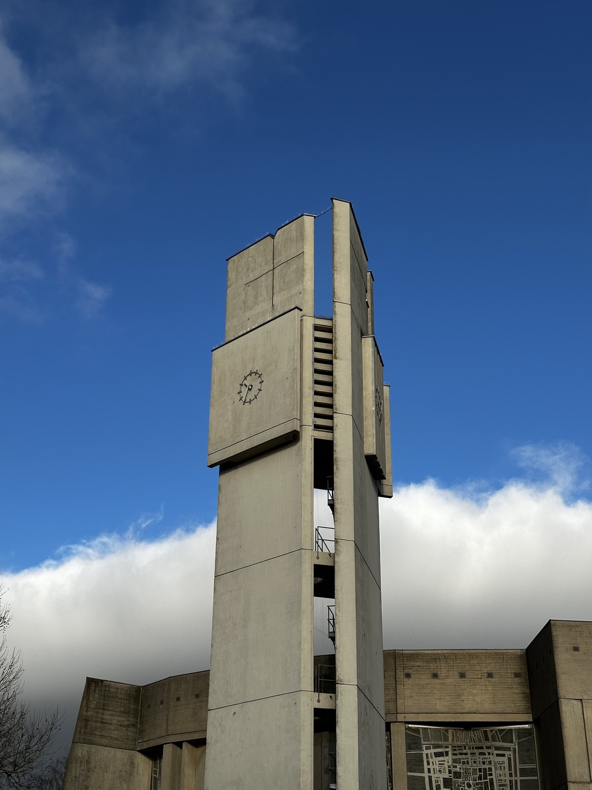 Betonturm mit Uhr vor blauem Himmel